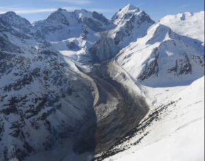 a long streak of rubble in a glacial channel below snowy mountains